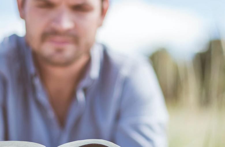 man reading Bible in field